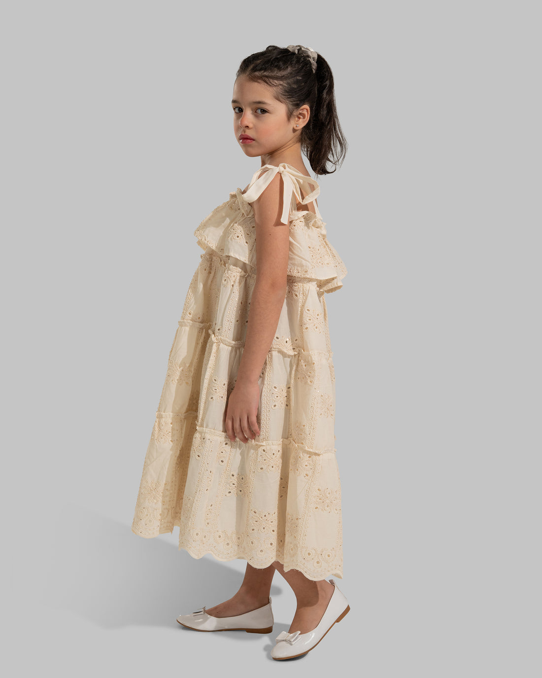 Tiered dress with perforated embroidery, ruffle trim, and tie-up shoulder straps.