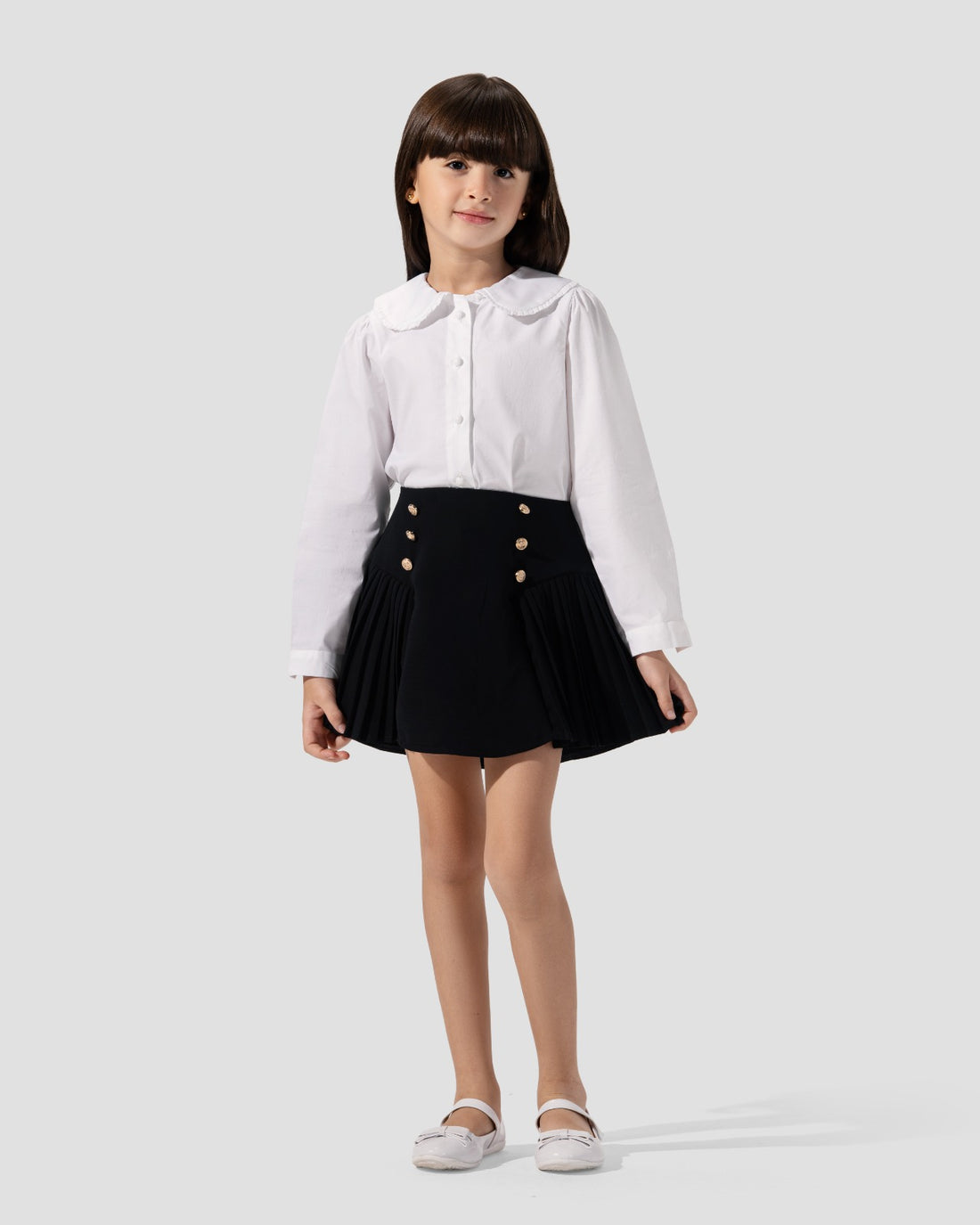 Short pleated skirt in navy blue with gold-tone button detail at the waist